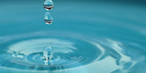 hellblaues Wasser mit Tropfen, die Ringe schlagen